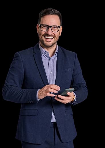 Jovem empresário sorrindo e olhando para a câmera com um celular na mão